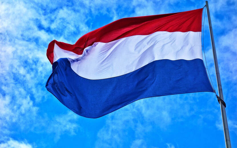De Nederlandse vlag wappert met een blauwe lucht erachter.
